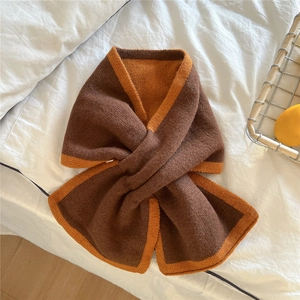 Détail d'une écharpe en tricot bicolore marron et orange avec fermeture croisée stylée