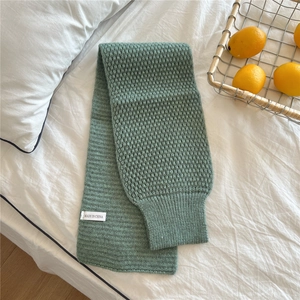 Detail of sage green chunky knit scarf with honeycomb texture and ribbed edge