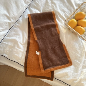 Gros plan d'une écharpe en maille bicolore marron et orange avec étiquette de soin