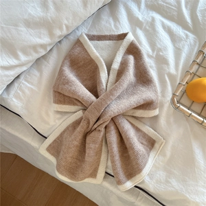Détail de l'écharpe en tricot bicolore camel et crème avec un design croisé élégant