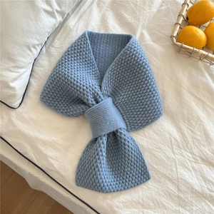 Detail of blue chunky knit scarf with a stylish bow-knot design on white bedding