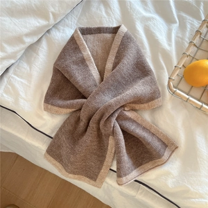 Détail d'une écharpe en maille marron et beige montrant le tissage épais et le style croisé