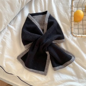 Détail de l'écharpe en tricot avec bords bicolores noir et gris sur fond de tissu blanc