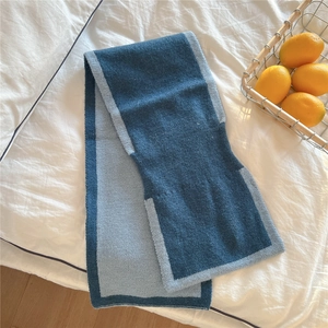 Gros plan d'une écharpe en maille bicolore bleue sur tissu blanc avec citrons frais