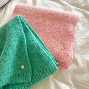 Detailed texture of fuzzy knit scarf with ribbed edge and golden logo badge