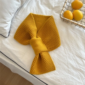 Detail of ginger yellow knitted scarf featuring textured pineapple stitch and cross-loop
