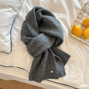 Close-up of dark grey knitted scarf featuring a premium gold round metal detail