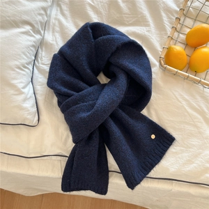 Detailed knit texture of a thick navy blue winter scarf with a golden metal button detail