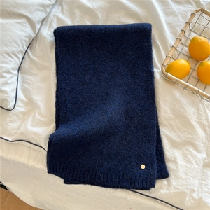 Detail of navy blue knitted scarf texture with small gold metal button decoration