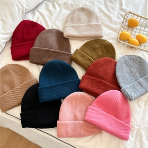 Detailed flat lay of ribbed knit beanies in 11 colors on white fabric background
