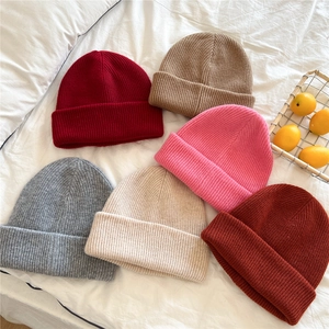 Thick ribbed knit beanies in multiple colors displayed on a soft white fabric surface