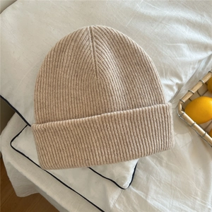 Detail of beige ribbed knit beanie featuring thick texture and classic folded cuff design