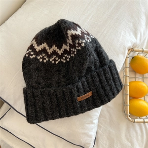 Close-up of thick grey knit hat featuring a brown leather patch and jacquard pattern