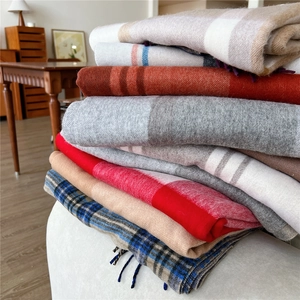 Collection of wool-like plaid and solid scarves with elegant fringe in autumn colors