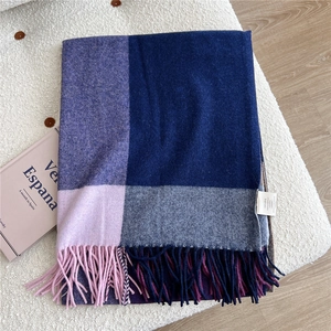 Detail of 100% wool scarf showing multicolor plaid texture and thick tassel fringe