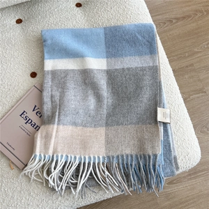 Close-up of premium checkered wool scarf with long tassels in blue and beige tones
