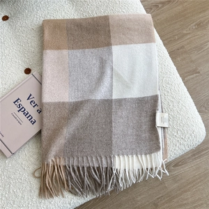Detail of 100% wool scarf featuring earthy plaid pattern and soft textured tassels