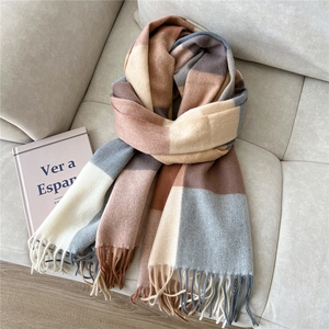 Detailed texture of a plaid wool scarf with long tassels on a beige fabric background