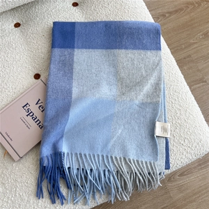 Close-up of blue and grey checkered wool scarf with fringes on white boucle background