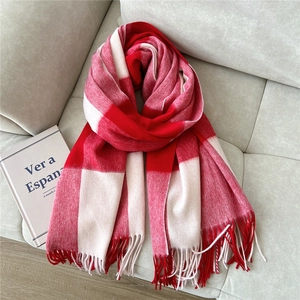 Macro detail of thick wool scarf with red and white grid pattern and long tassels