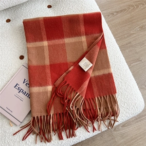 Detail of red-brown wool scarf featuring classic large check pattern and thick tassels