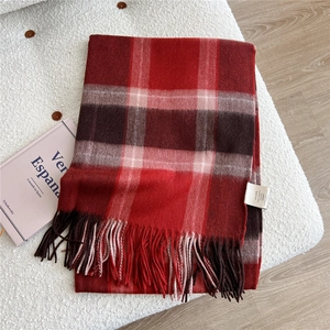 Close-up of red plaid wool scarf showing 100% wool label and soft fringe texture