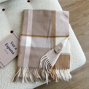 Close-up of 100% wool scarf with beige and caramel checks and long white tassels
