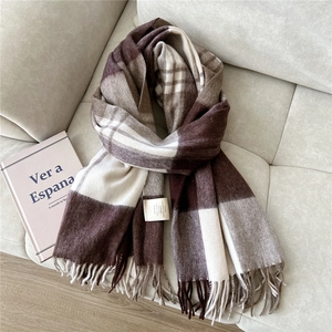 Detail of 100% wool scarf featuring brown plaid patterns and soft fringed edges