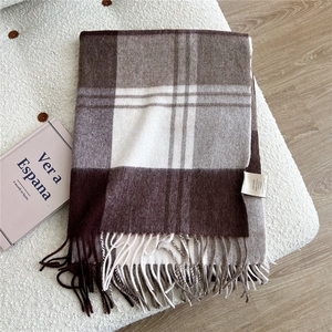 Detail of 100% wool scarf featuring classic brown plaid patterns and soft fringe edges