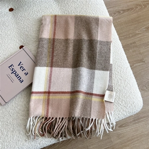 Detail of 100% wool scarf featuring classic earth-tone plaid patterns and fringe edges