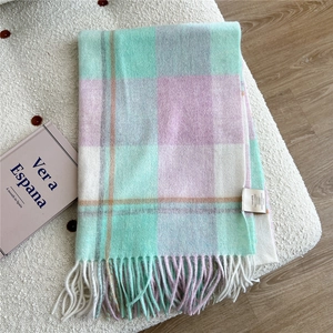 Detail of 100% wool scarf featuring mint green and lilac plaid with fringed edges