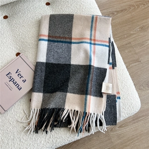 Detail of wool scarf showing 100% wool label, fringe edge and classic plaid pattern