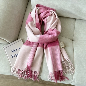 Close-up of a pink checkered wool scarf with fringes, showing soft texture and premium quality