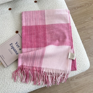 Close-up of pink checkered wool scarf with long tassels and 100% wool material label