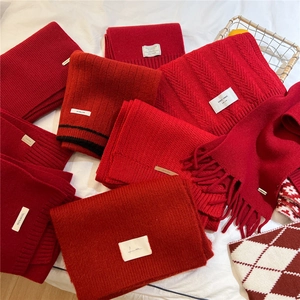 Close-up of assorted red wool knit scarves with fringe details in diverse textures