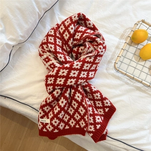 Red festive knitted scarf with white floral patterns and ribbed edges on white linen