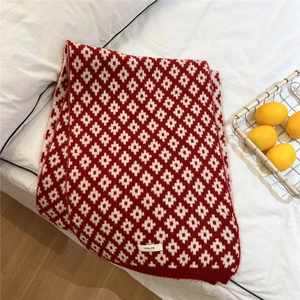 Detail of red and white knit scarf with star pattern and brand label on white bedding