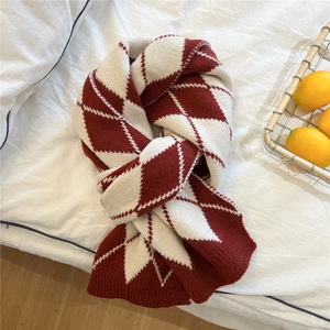Detail of thick red and white argyle knit scarf with ribbed edges on soft fabric