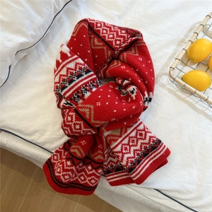 Close-up of red knitted scarf with Nordic jacquard patterns and soft winter texture