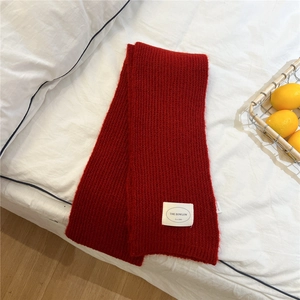 Close-up of red knitted winter scarf with soft texture and white brand woven label