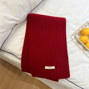 Detail of red wool scarf featuring thick ribbed texture and 100% wool material label