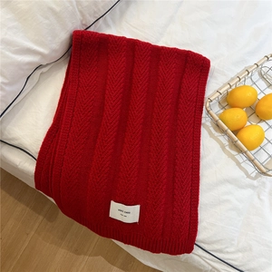 Close-up of red chunky knit scarf with V-shape cable patterns and white brand label
