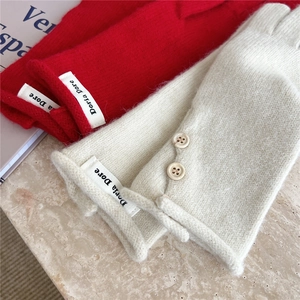 Detail of thick knitted gloves with buttons and brand label on marble surface