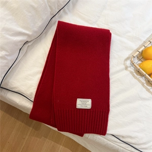 Detail shot of the 100% wool red knitted scarf texture and white material label