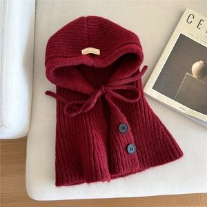 Detailed knit texture of a wine red hooded winter scarf with handmade label on a sofa