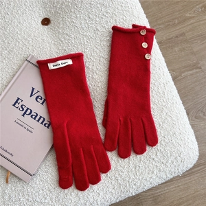 Detail of red knitted touchscreen gloves with vintage brown buttons on soft fleece