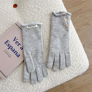 Close-up of light gray knitted winter gloves with wooden buttons on soft white fleece