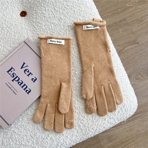 Detail of camel knitted gloves with button accent and woven label on soft fleece