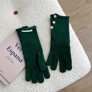 Close-up of forest green knitted gloves featuring three wooden buttons on fleece background
