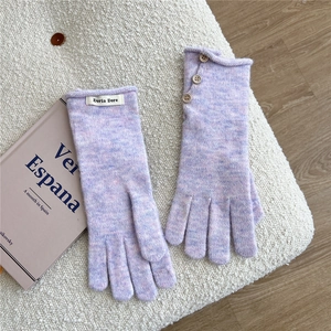 Close-up of purple knit glove with three brown decorative buttons on the wrist cuff